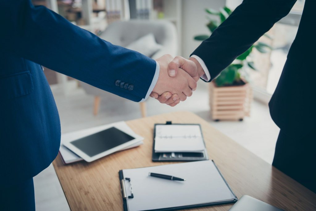 two male hands shaking over table desk