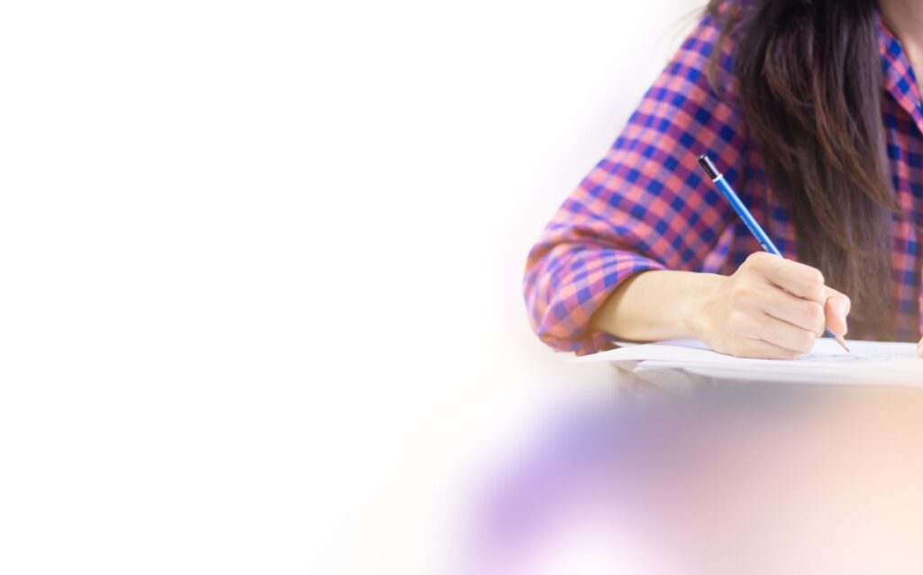 high school student holding pencil writing on paper answer sheet