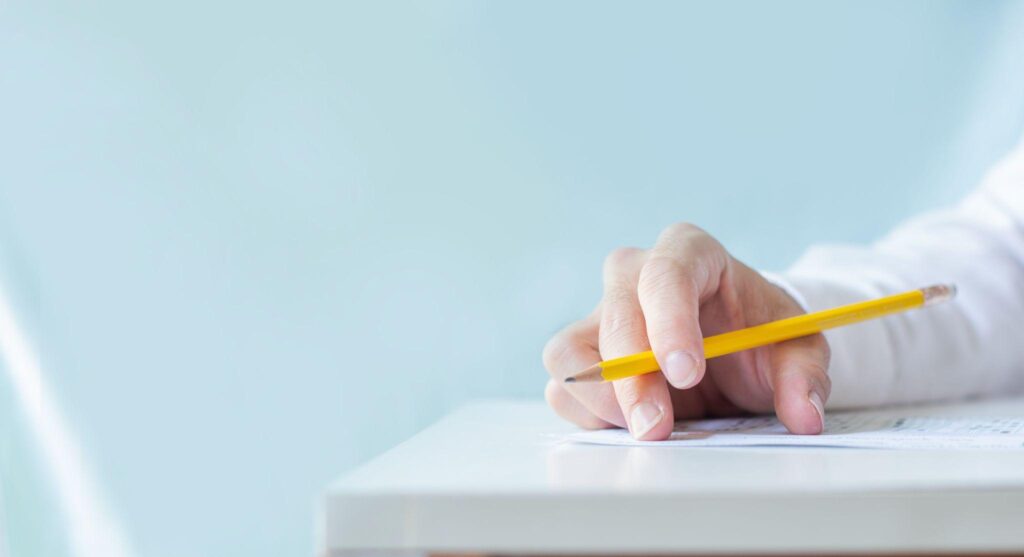 hands holding pencil writing paper answer sheet.